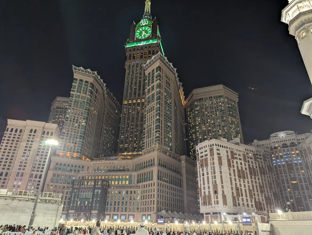 The Abraj Al-Bait clock tower illuminated at night above the Grand Mosque in Makkah